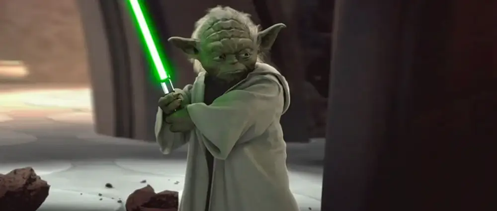 Yoda holding a green lightsaber.